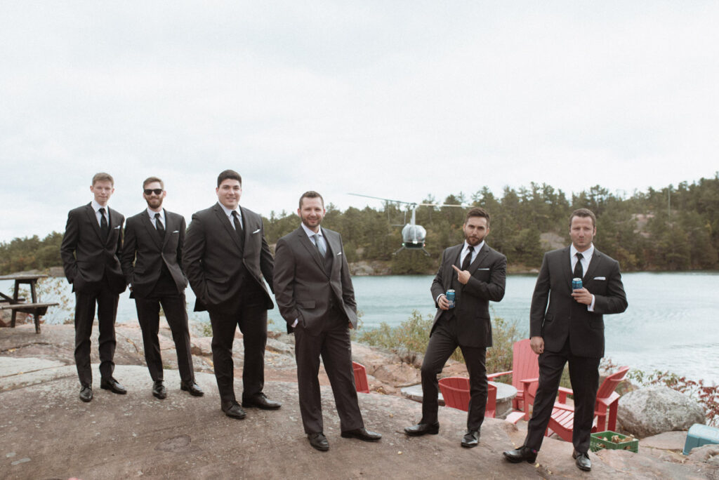 Killarney Mountain Lodge Wedding - Groom and groomsmen posing with a helicopter on a rock with Georgian Bay behind them. 