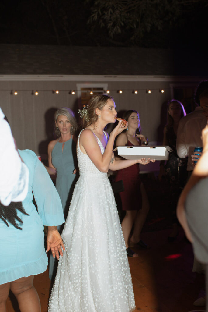Sudbury backyard wedding reception bride eating pizza on the dance floor.