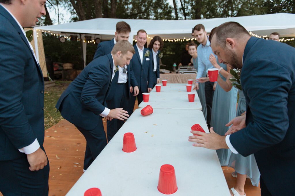 Sudbury backyard wedding party, bride and groom playing a game of flip cup. 