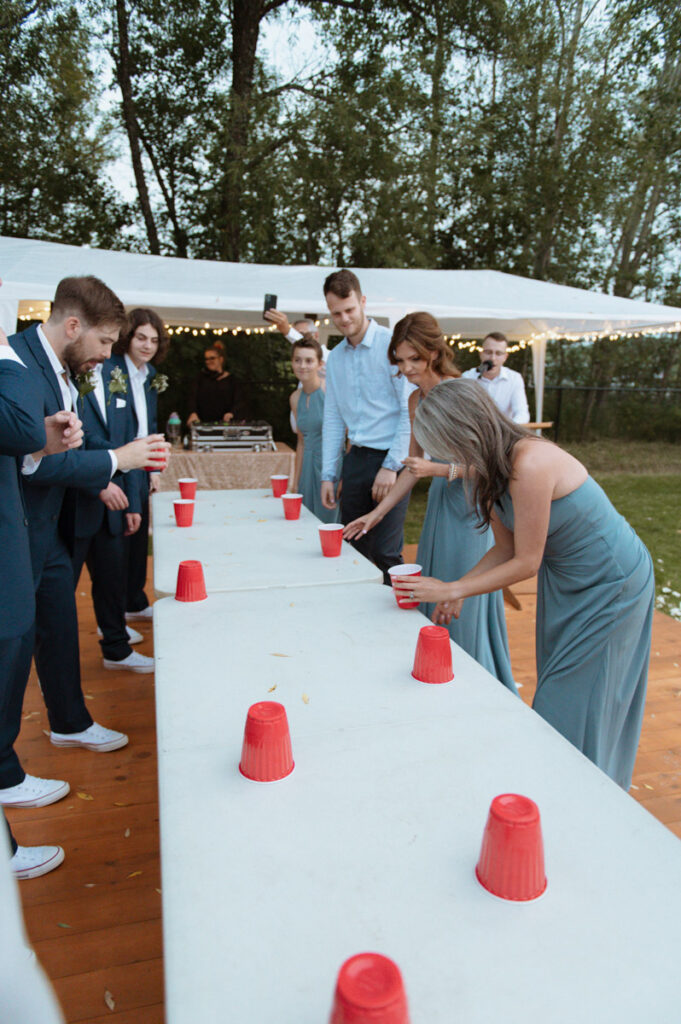 Sudbury backyard wedding party, bride and groom playing a game of flip cup. 