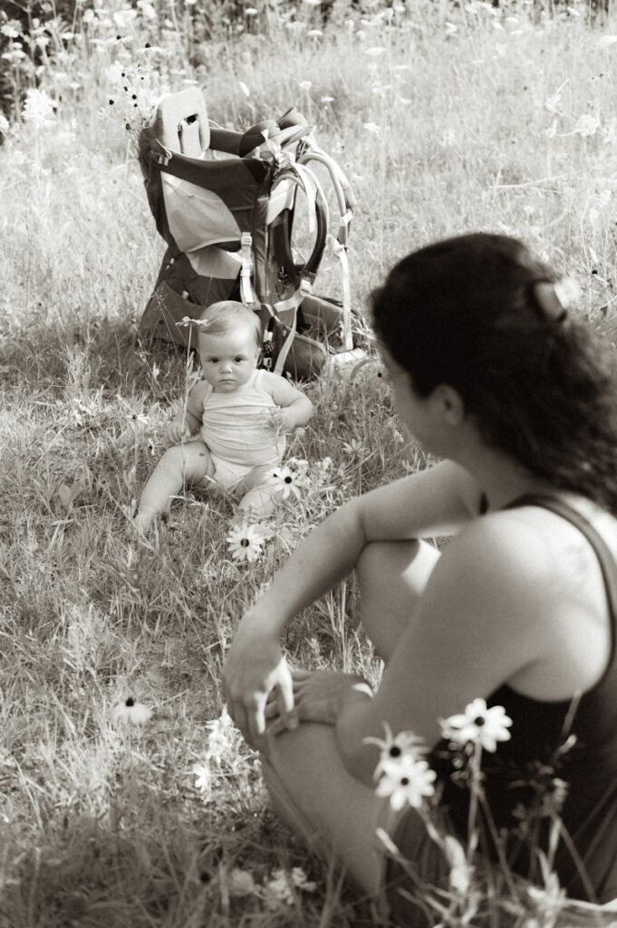 Little girl sitting with mother in Sudbury field documented by a Sudbury photographer. 