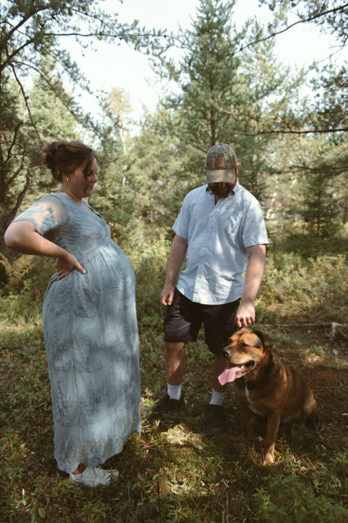 male and pregnant female couple in a field with a dog by an Ontario Documentary Photographer 