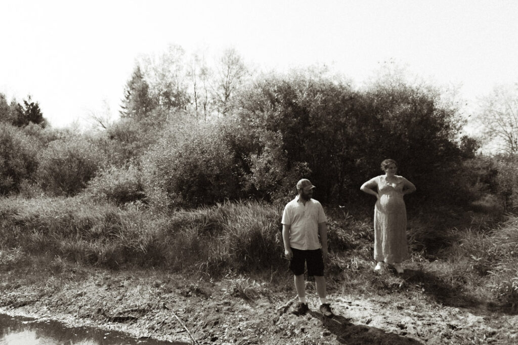 male and pregnant female couple by a river with a dog by an Ontario Documentary Photographer 