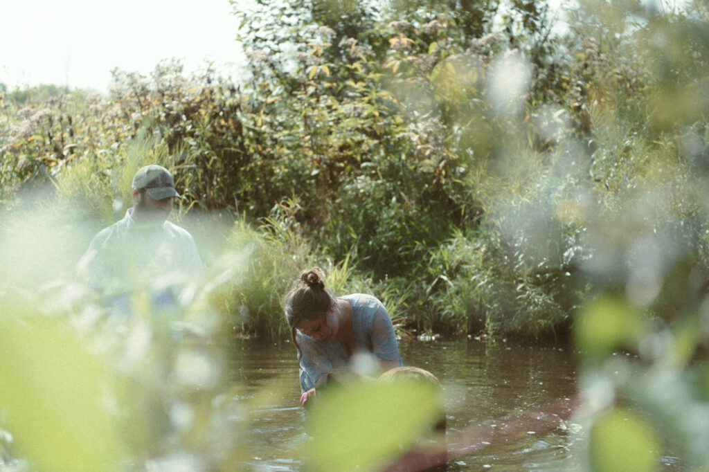 male and pregnant female couple in a river with a dog by an Ontario Documentary Photographer 