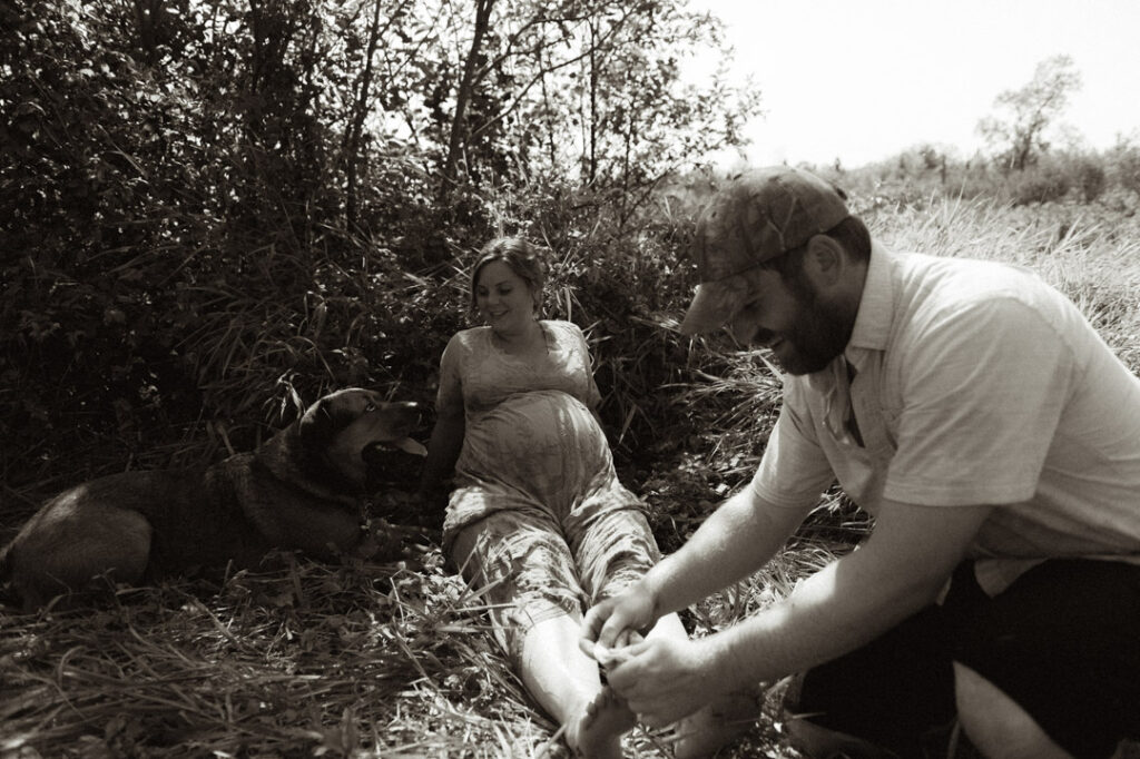 male and pregnant female couple in a field with a dog by an Ontario Documentary Photographer 