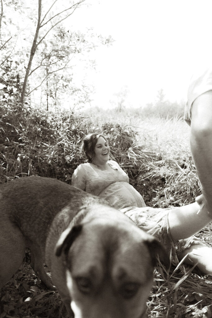 male and pregnant female couple in a field with a dog by an Ontario Documentary Photographer 