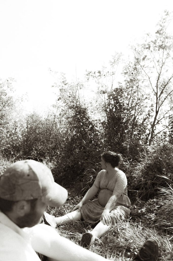 male and pregnant female couple in a field with a dog by an Ontario Documentary Photographer 