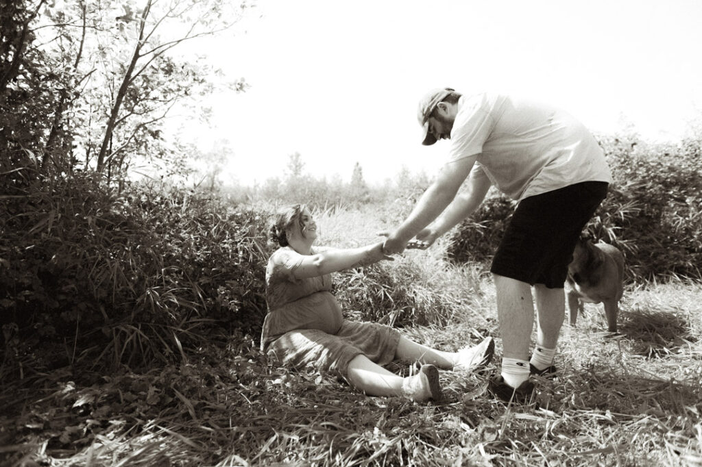 male and pregnant female couple in a field with a dog by an Ontario Documentary Photographer 