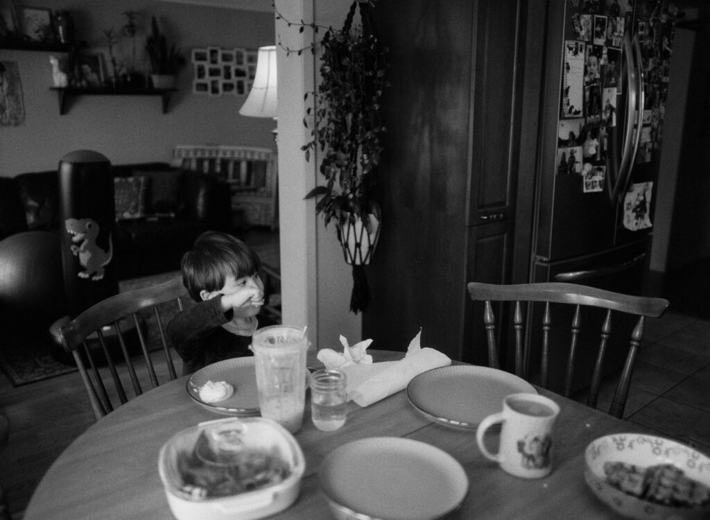Family at a kitchen table eating breakfast in their pjs documented by a Sudbury Family Photographer. 