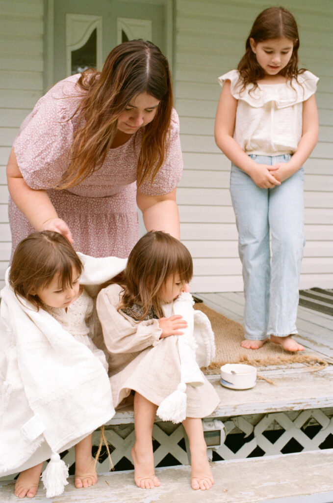 A mom and her 3 daughters on the front porch eating cereal documented by a Sudbury motherhood photographer