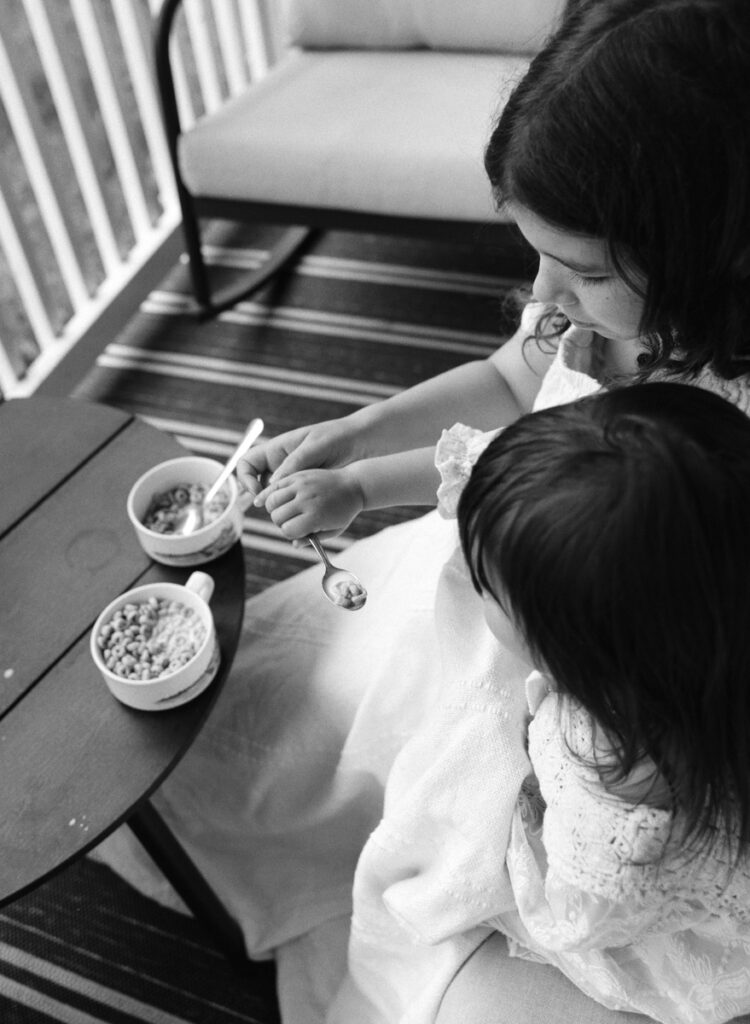 A mom and her 3 daughters on the front porch eating cereal documented by a Sudbury motherhood photographer